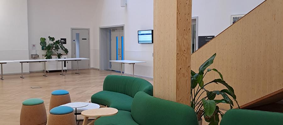 A room with green sofas and small stools